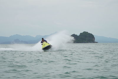 People on boat in sea against sky