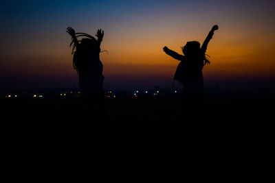 Silhouette men against illuminated sky at night
