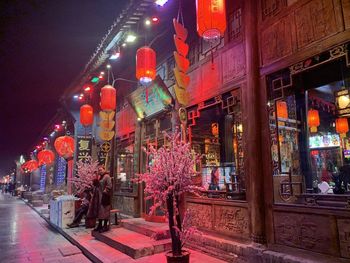 Illuminated street amidst buildings in city at night