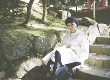 Woman sitting on steps by tree