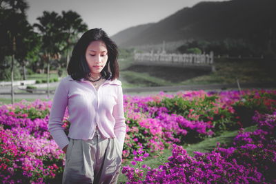 Woman standing by pink flowers on field