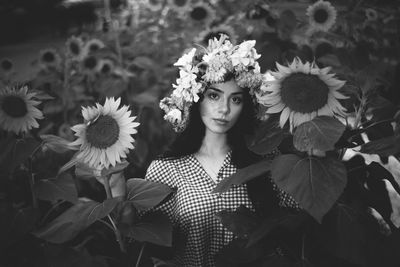 Portrait of young woman standing amidst sunflower field