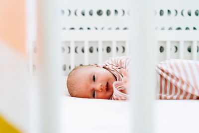 Straight on portrait of a baby girl laying in her modern crib