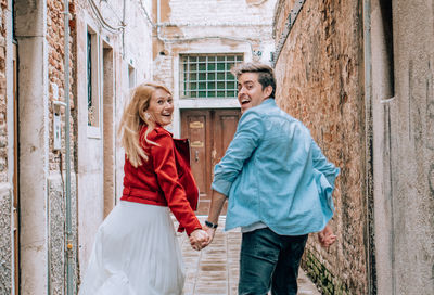 Portrait of young couple running on footpath