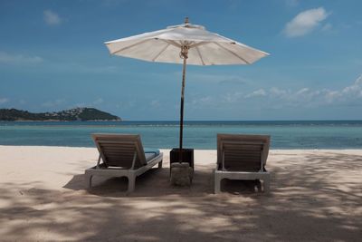 Deck chairs on beach against sky