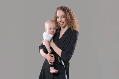 Business woman in black jacket holds baby in her arms. mother and little son