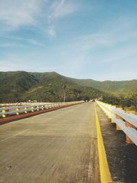 Empty road along landscape and mountains against sky
