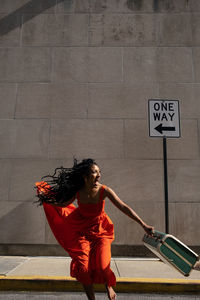 Smiling woman jumping with her suitcase 