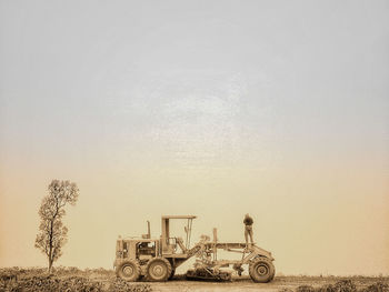 Man standing on tractor against sky