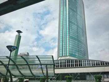 Low angle view of modern building against cloudy sky