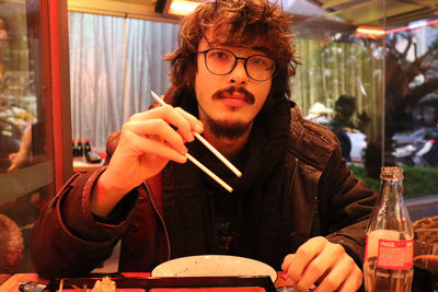 Portrait of man holding chopsticks at restaurant