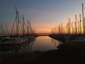 Sailboats moored at harbor during sunset