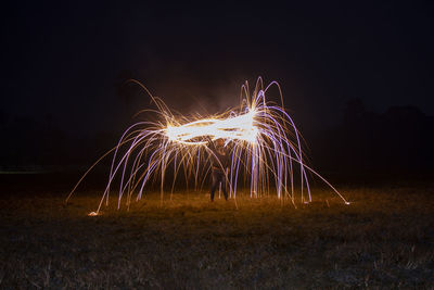 Light trails on field against sky at night