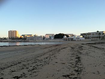 Beach by city against clear sky