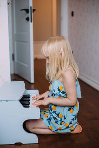 Little blonde girl plays a toy piano at home. musical development in childhood