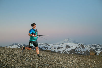 Rear view of boy standing on mountain against clear sky