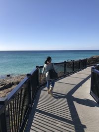 Full length of woman standing near railing against sea