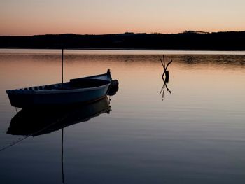 Boat moored in lake against sky during sunset