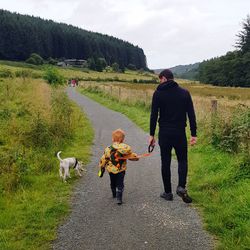 Rear view of people with dog walking through dalby forest 