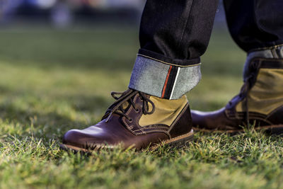 Low section of man wearing shoes on grass