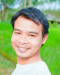 Close-up portrait of man smiling while standing at rice paddy