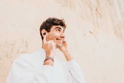 Man with in ear headphones standing near wall