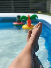 Low section of child relaxing by swimming pool