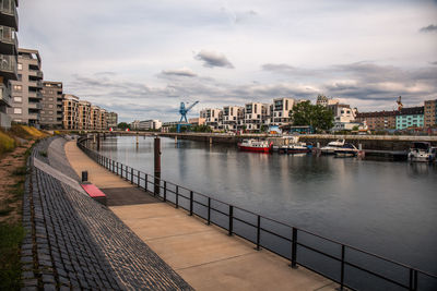 Bridge over river by buildings in city against sky