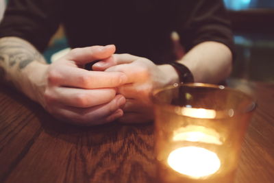 Close-up of tea light by man at table