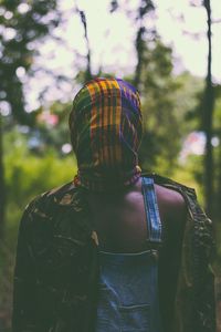 Rear view of man standing by tree in forest