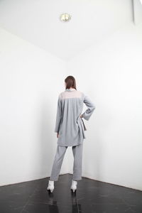 Young woman standing against white wall