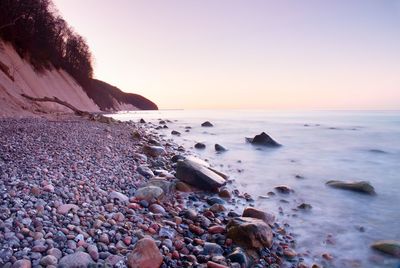 Romantic morning at sea. big boulder in smooth wavy sea. long exposure for smooth dreamy water level