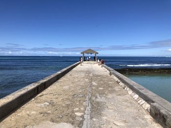 Pier on beach against blue sky