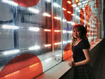 Young woman looking away while standing on illuminated walkway