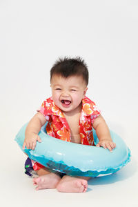 Cute baby boy with inflatable ring against white background