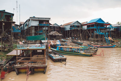 Boats moored on a river by houses against sky