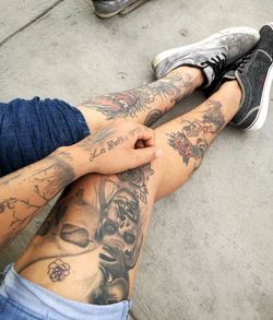 Low section of tattooed friends on footpath