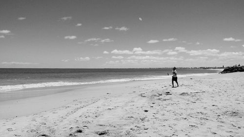 Woman walking on beach against sky