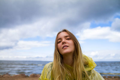 Portrait of smiling young woman against sea at beach