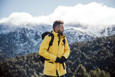 Young man standing on mountain during winter