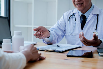 Midsection of man holding hands on table