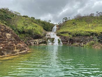 Scenic view of waterfall against sky