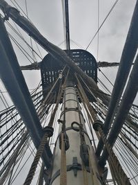 Low angle view of tall ship mast against cloudy sky