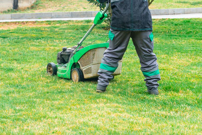 Low section of man working on grassy field