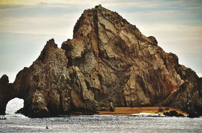 Rock formations on beach against sky