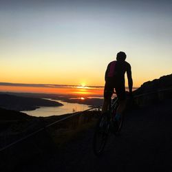 Silhouette man riding bicycle during sunset