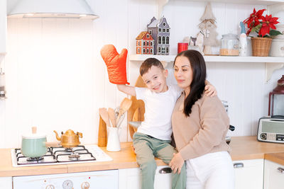 Fun mom and son playing in kitchen, happy spending time on christmas eve