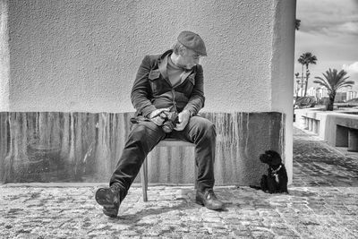 Man with dog sitting against wall