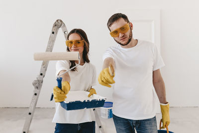 Happy smiling married couple engaged in renovation repair in the room of the house preparing to move