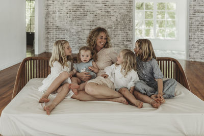 Mother and daughters looking at each other lovingly on studio couch